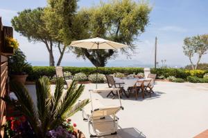 un patio con mesa, sillas y sombrilla en Holidaycasa Circe - Con giardino vista mare, en Terracina