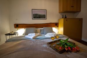 a bed with two glasses of wine and flowers on it at Apartman TALIJA in Pirot