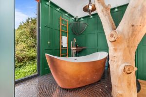 a bathroom with a bath tub and a tree in the corner at Ivy Cottage Holiday Cabins in Southampton