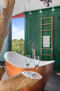 uma casa de banho com banheira e 2 copos de vinho em Ivy Cottage Holiday Cabins em Southampton