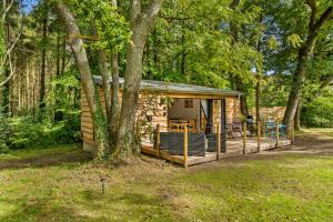 eine Blockhütte im Wald mit einem Baum in der Unterkunft Ivy Cottage Holiday Cabins in Southampton