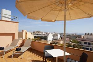 einen Balkon mit Tischen, Stühlen und einem Sonnenschirm in der Unterkunft Sercotel Hotel Zurbarán Palma in Palma de Mallorca