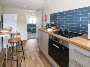 a kitchen with blue tile on the wall and a stove at Monarch in Weymouth