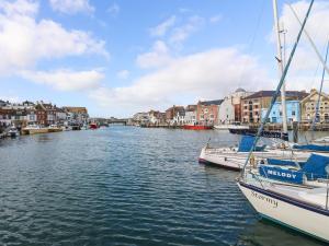 a couple of boats docked in a river with buildings at Monarch in Weymouth