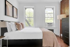 1 dormitorio con 1 cama blanca y 2 ventanas en Sunlit LES 1BR w WD nr BD train NYC-865, en Nueva York