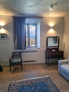 een woonkamer met een bank, een tv en een raam bij Casa Mustiola in Montalcino