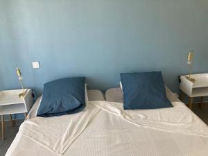ein Bett mit zwei blauen Kissen darüber in der Unterkunft Appartement Le Lavandou, 2 pièces, 4 personnes - FR-1-308-167 in Le Lavandou