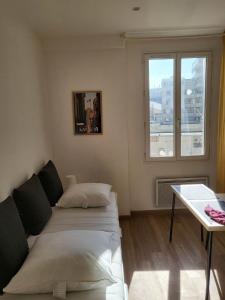 a bedroom with a bed and a table and a window at Studio sur le port de Toulon in Toulon