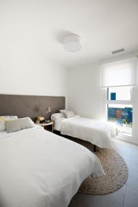 2 Betten in einem weißen Zimmer mit Fenster in der Unterkunft Turquesa del Mar - Max Beach Golf - Large Sunny Terrace Apartment in Playa Flamenca
