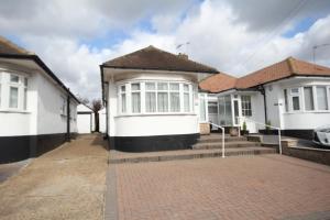 a row of white houses with a driveway at The Ruislip Bungalow in Ruislip