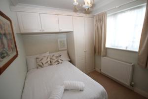 a small bedroom with a white bed and a window at The Ruislip Bungalow in Ruislip