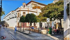a building with people sitting in front of it on a street at Alleanza, Aires de Guadalquivir in Seville