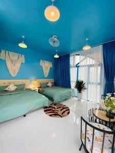 a blue bedroom with two beds and a table at Cau May Tam Dao - Venuestay in Tam Ðảo