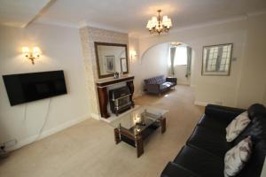 a living room with a black couch and a tv at The Ruislip Bungalow in Ruislip