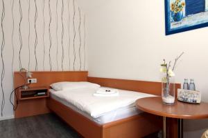 a small bedroom with a bed and a table at Hotel Messeblick in Sarstedt