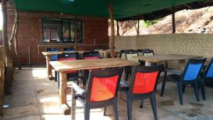 a group of wooden tables and chairs under an umbrella at Vinee's Kitchen and Motel in Koynanagar