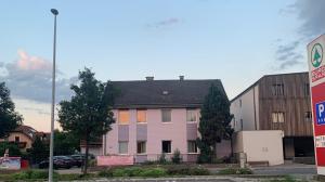 a white house with a black roof in a parking lot at Appartementhaus Lekic in Böheimkirchen