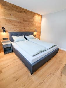 ein Schlafzimmer mit einem großen Bett und einer Holzwand in der Unterkunft Ferienhaus Altstadtchalet in Schmallenberg