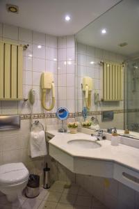 een badkamer met een wastafel, een toilet en een spiegel bij Denizatı Plus Hotel in Istanbul