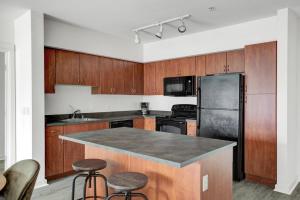 a kitchen with wooden cabinets and a stainless steel refrigerator at Downtown Bellevue 2BR w WD Storage nr Shops SEA-222 in Bellevue
