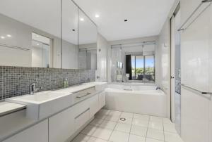 a white bathroom with two sinks and a tub at Luxury Apartments at Bells Blvd in Kingscliff