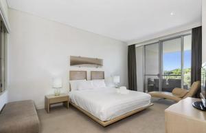 a white bedroom with a bed and a living room at Luxury Apartments at Bells Blvd in Kingscliff