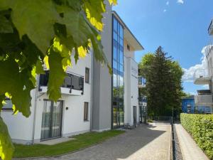 ein weißes Gebäude mit Glasfenstern auf einer Straße in der Unterkunft Dünenhaus Aurell in Heringsdorf