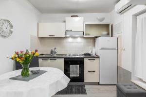 a kitchen with white appliances and a table with flowers at Studio Toniko in Split