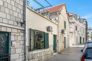 a street with buildings with green shutters and a window at Studio Toniko in Split