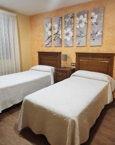 two beds in a hotel room with flowers on the wall at Saint James Way in Cacabelos