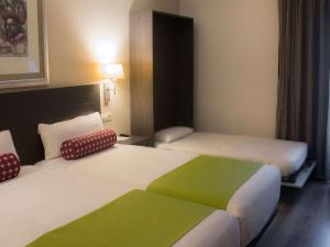 a hotel room with two beds with green and white at Mercure Madrid Centro in Madrid