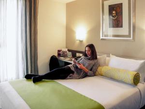 a woman sitting on a bed in a hotel room at Mercure Madrid Centro in Madrid