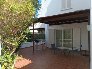 a patio with chairs and a table in front of a house at DUPLEX ESPECTACULAR en PRIMERA LÍNEA NATURISTA! in Las Bombardas