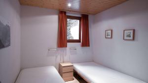 a small room with two beds and a window at Stachelbeere UG in Fiesch