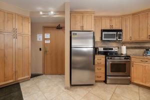 um frigorífico de aço inoxidável numa cozinha com armários de madeira em Iron Horse C5083 condo em Winter Park