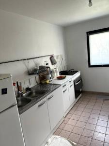 a kitchen with white cabinets and a sink and a stove at Grand appartement lumineux in Noisy-le-Grand