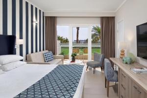a hotel room with a bed and a living room at Neptune Eilat By Dan Hotels in Eilat