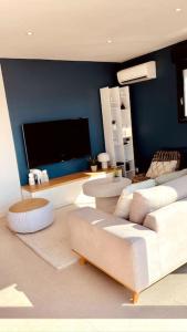 a living room with a white couch and a tv at Romy YourHostHelper in Saint-Cyr-sur-Mer