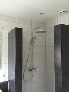 a shower with a shower head in a bathroom at Herberg het Landhuis in Schoorl