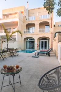 a patio with chairs and a pool in front of a building at The Carob Tree in Victoria