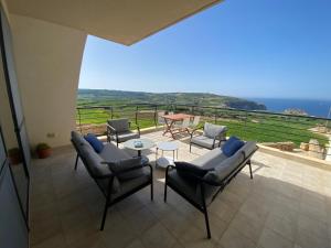 een patio met stoelen en een tafel en uitzicht op de oceaan bij Gozo Dwejra Views in San Lawrenz