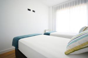 two beds in a bedroom with a window at Precioso apartamento con piscina en Sanxenxo in Sanxenxo