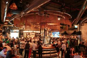 a crowd of people standing around a bar in a room at FIVE Jumeirah Village in Dubai