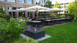 a restaurant with tables and umbrellas in a courtyard at Motel One München-Campus in Munich