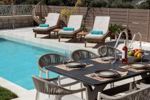 a dining table and chairs next to a swimming pool at Villa Silentium Evilia by PosarelliVillas in Aryiroúpolis