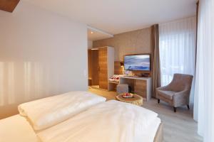 フロイデンシュタットにあるホテル トイヒェルヴァルトのベッド、椅子、テレビが備わるホテルルームです。