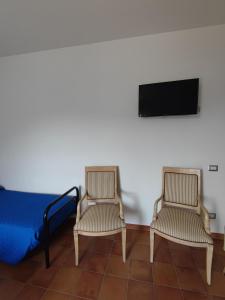 2 Stühle und 1 Bett in einem Zimmer mit einem TV in der Unterkunft Hermitage Ravello in Ravello