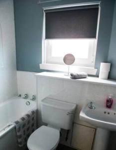 a bathroom with a toilet and a sink and a window at Cunninghame 2 in Beith