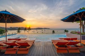 einen Pool am Strand mit Stühlen und Sonnenschirmen in der Unterkunft Bandara Phuket Beach Resort in Panwa Beach