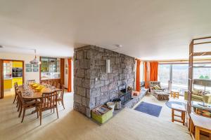 a large stone fireplace in a living room with a table at Bells View in Kippford